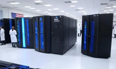 A high-tech manufacturing facility in the United States showcasing NVIDIA's DGX GH200 AI supercomputers with Hopper architecture, featuring rows of advanced systems with glowing blue lights, an American flag in the background, and researchers in white coats, symbolizing U.S. technological advancement and sovereignty.