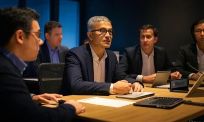 Business meeting of tech executives discussing AI transformation in 2025, featuring laptops and a modern conference room, representing the leadership of Microsoft, Google, and Amazon in cloud and AI, amidst challenges faced by Apple and hardware companies due to global trade impacts.