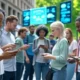 A diverse group of people using smartphones in a modern urban setting, showcasing technology improving daily life with apps for shopping, healthcare, and smart city management.