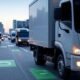 Modern tech landscape showcasing AI-powered route optimization for fleet management, featuring delivery vans with real-time route maps displayed on a large screen and individual monitors.