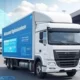 A modern logistics truck with an AI route optimization interface displayed on its side, parked in a warehouse lot with other trucks and a digital map overlay, symbolizing efficient delivery and reduced costs in logistics.