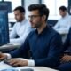 Team collaborating in a modern workplace with computers, showcasing AI-driven error reduction and efficiency.