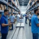 Warehouse workers using mobile scanners and tablets to manage real-time inventory visibility, with shelves of organized products and a conveyor belt in a modern facility, improving operational efficiency and customer satisfaction.
