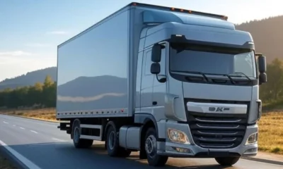 A modern delivery truck driving on a clear road with mountains and greenery in the background, representing AI-optimized logistics for efficient and safe deliveries.