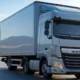 A modern delivery truck driving on a clear road with mountains and greenery in the background, representing AI-optimized logistics for efficient and safe deliveries.