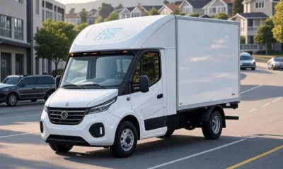 A modern white delivery truck equipped with AI and smart sensors navigating a suburban street, showcasing real-time last-mile tracking technology against a backdrop of homes and warehouses, improving delivery efficiency and customer visibility.